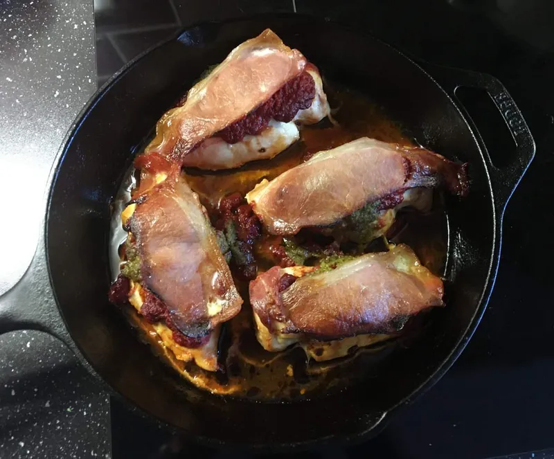 Chicken tomato pesto and bacon cooked in a cast iron skillet