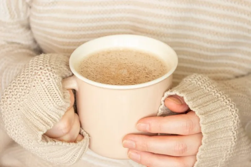 holding a hot drink to keep warm
