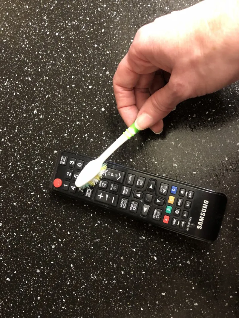 rubbing tv remote with a toothbrush