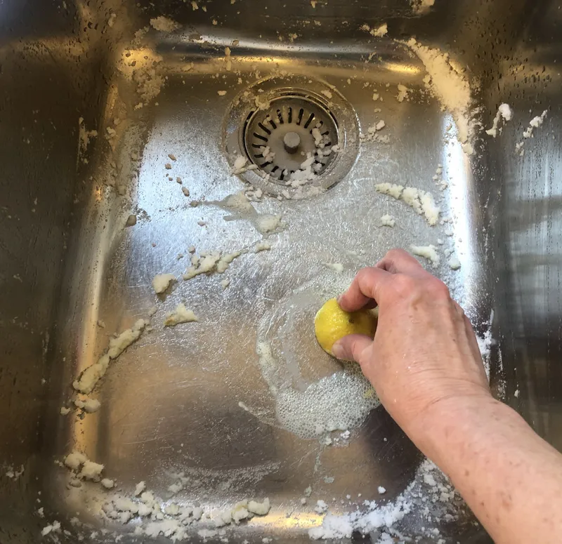 scrubbing a stainless-steel sink with lemon