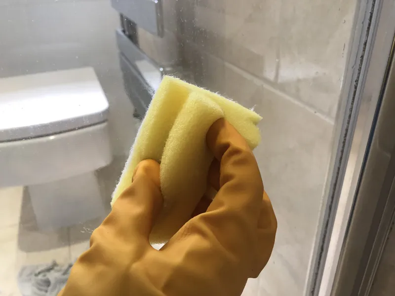 scrubbing the shower door with the scourer and dishwasher tablet