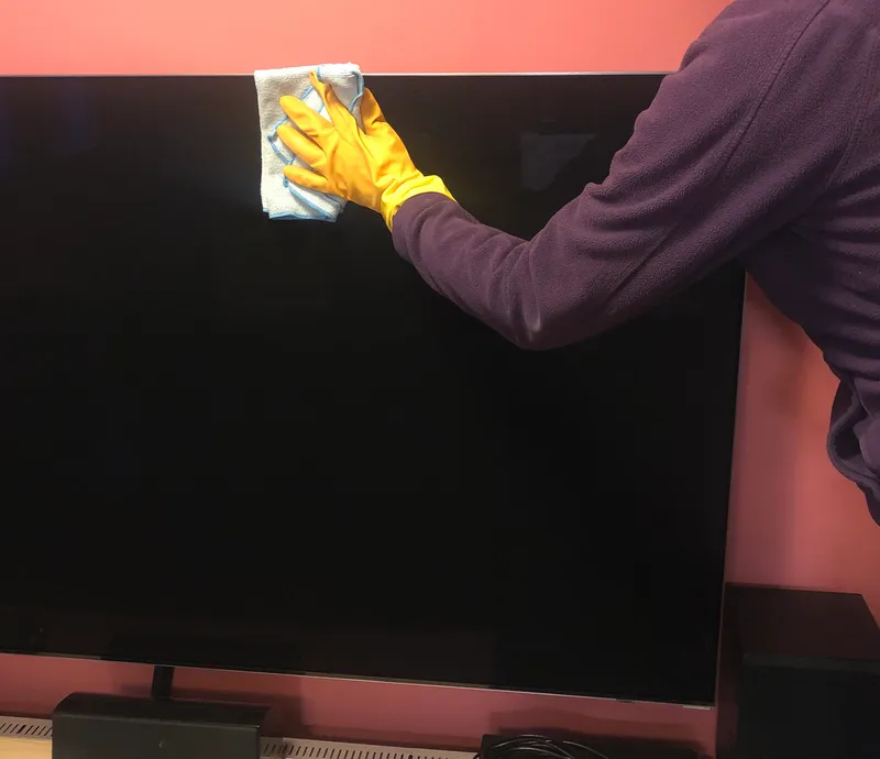 wiping a TV screen with a microfiber cloth