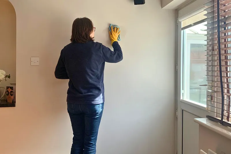 wiping the wall with a wet cloth