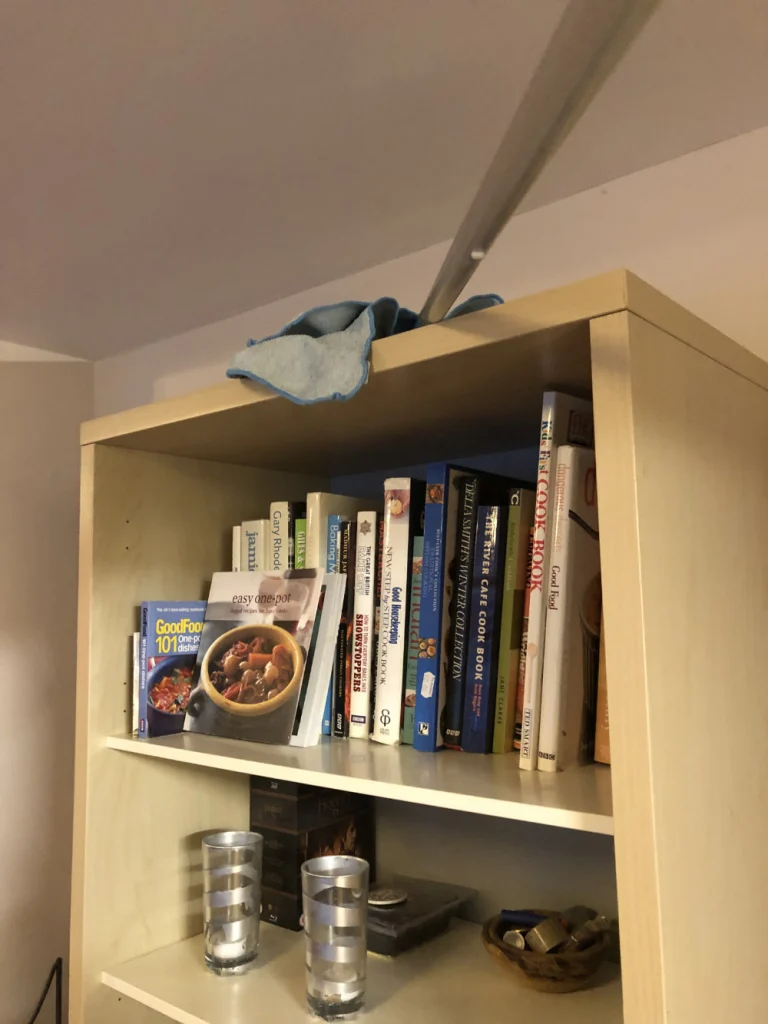 dusting the top of a bookcase