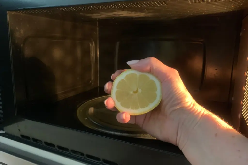 mão segurando meio limão no microondas