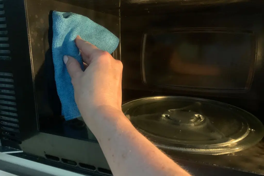 wiping the microwave with a microfiber cloth