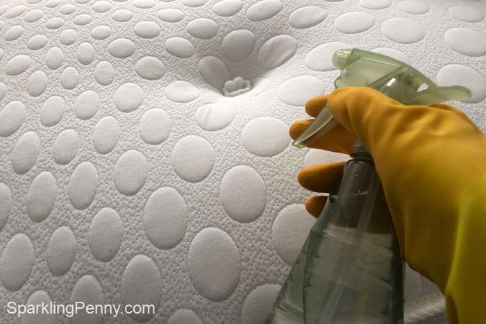 spraying a mattress with homemade dust mite spray