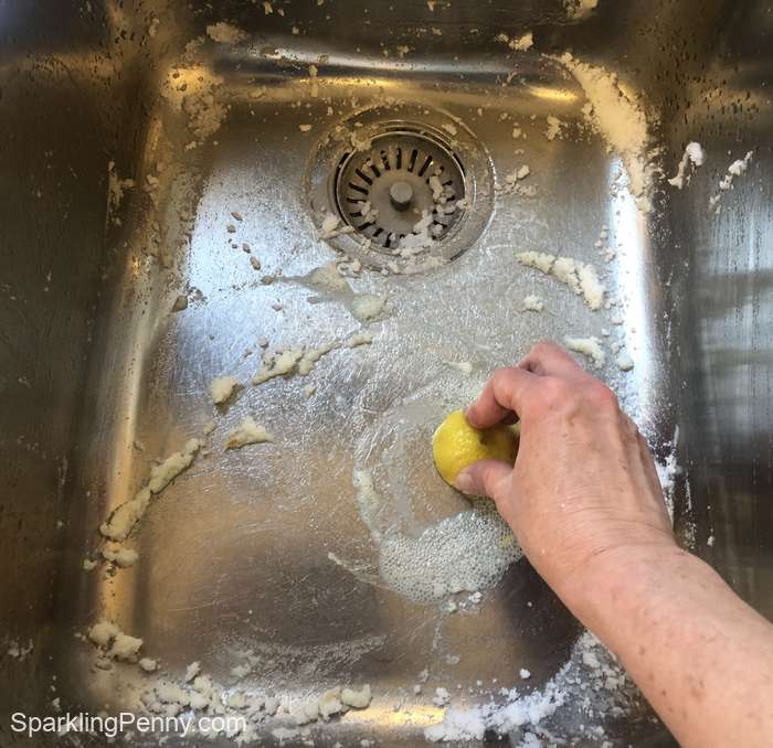 scrubbing a stainless-steel sink with lemon
