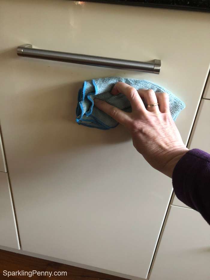 wiping a kitchen door with a damp microfiber cloth